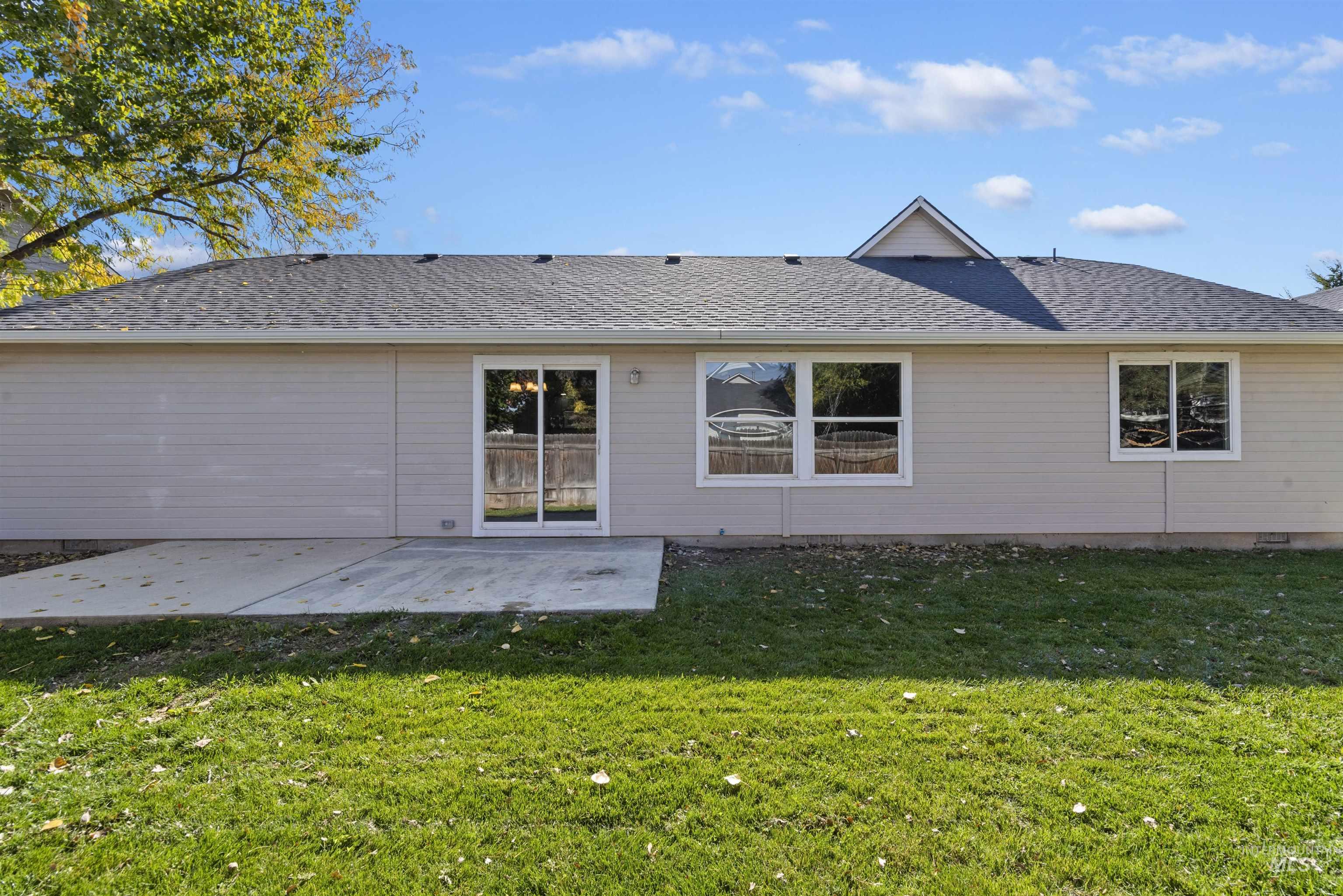 Back of house featuring roof with shingles, a patio area, and a lawn