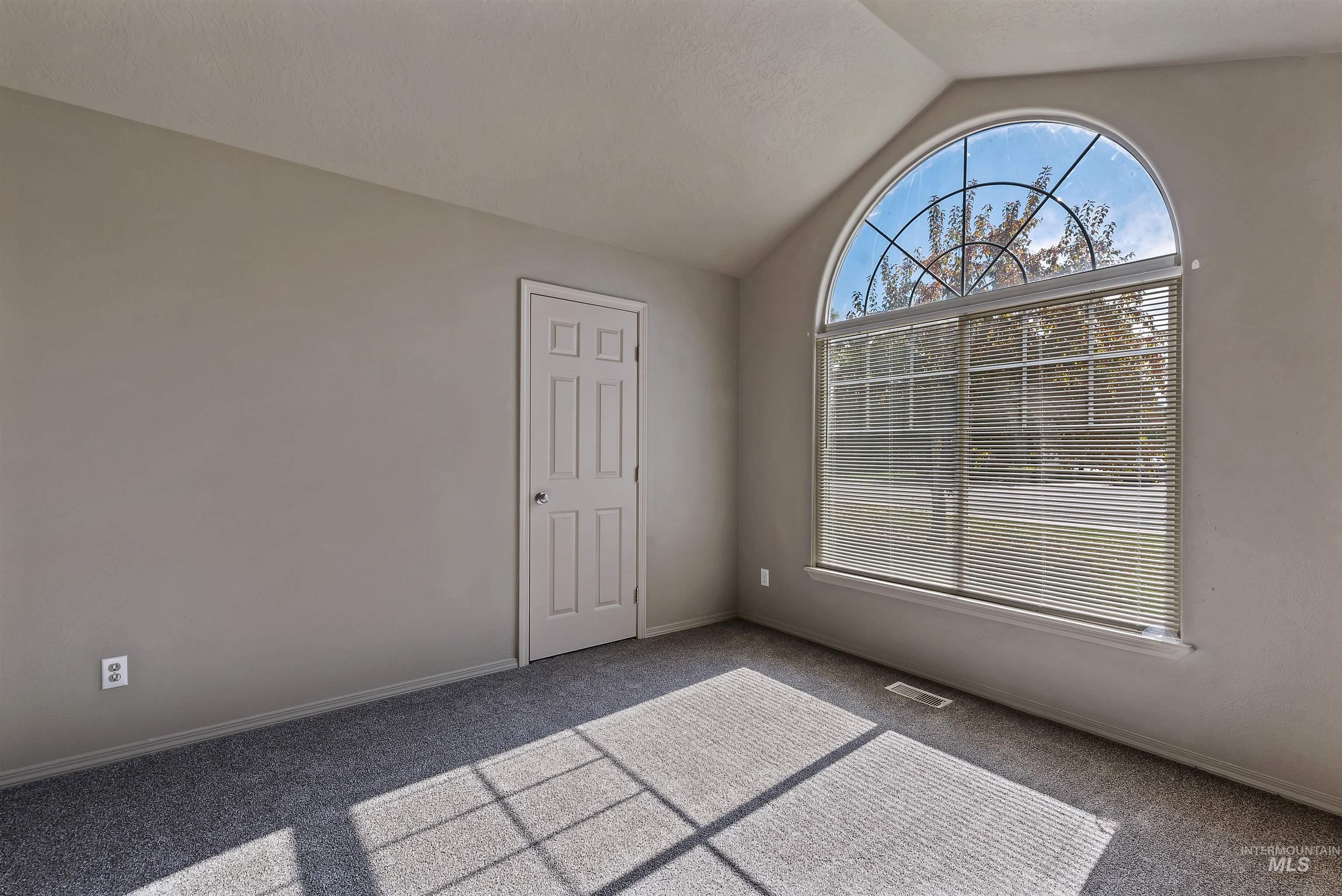 Carpeted empty room featuring lofted ceiling and baseboards