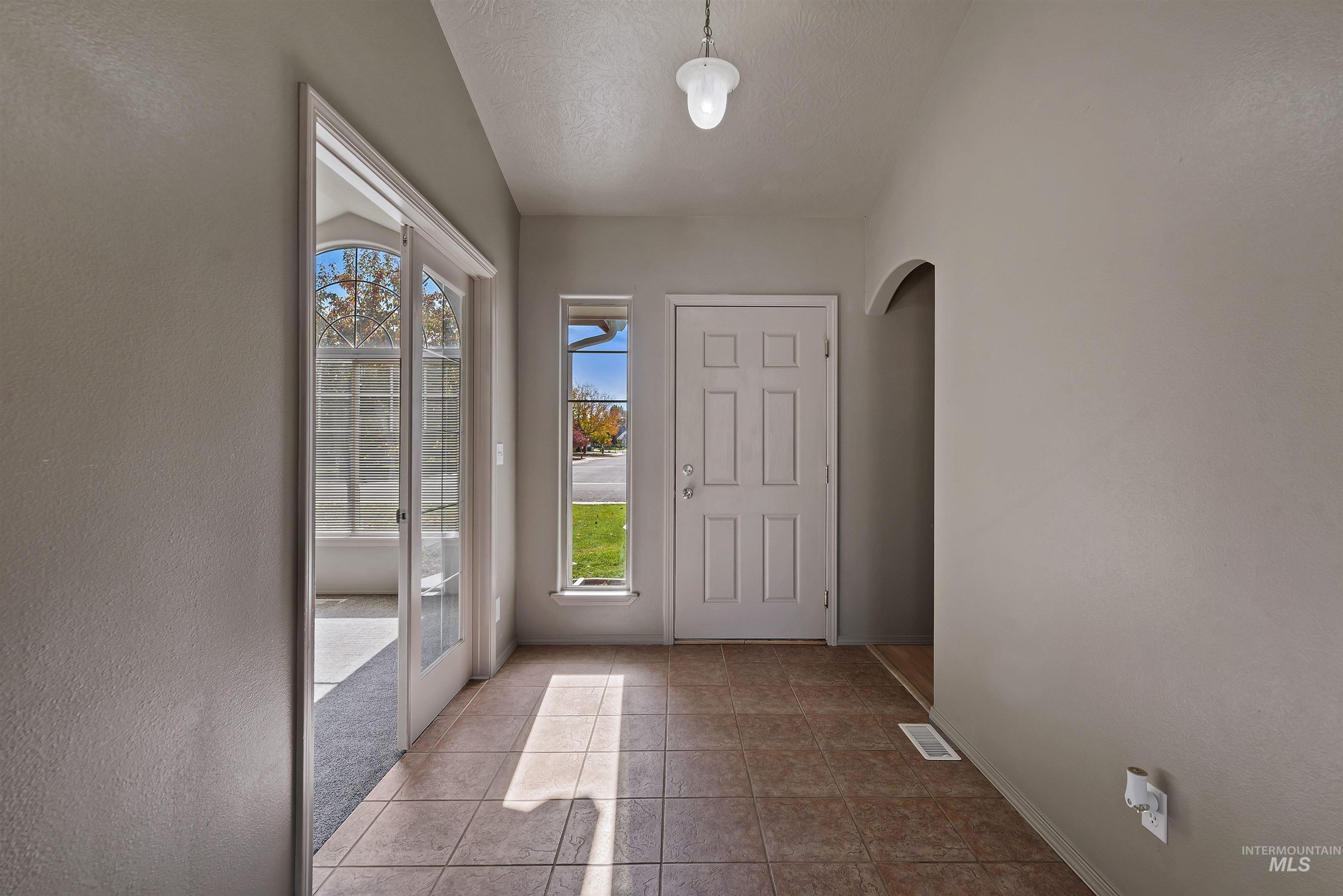 Tiled foyer entrance with a textured ceiling and a textured wall