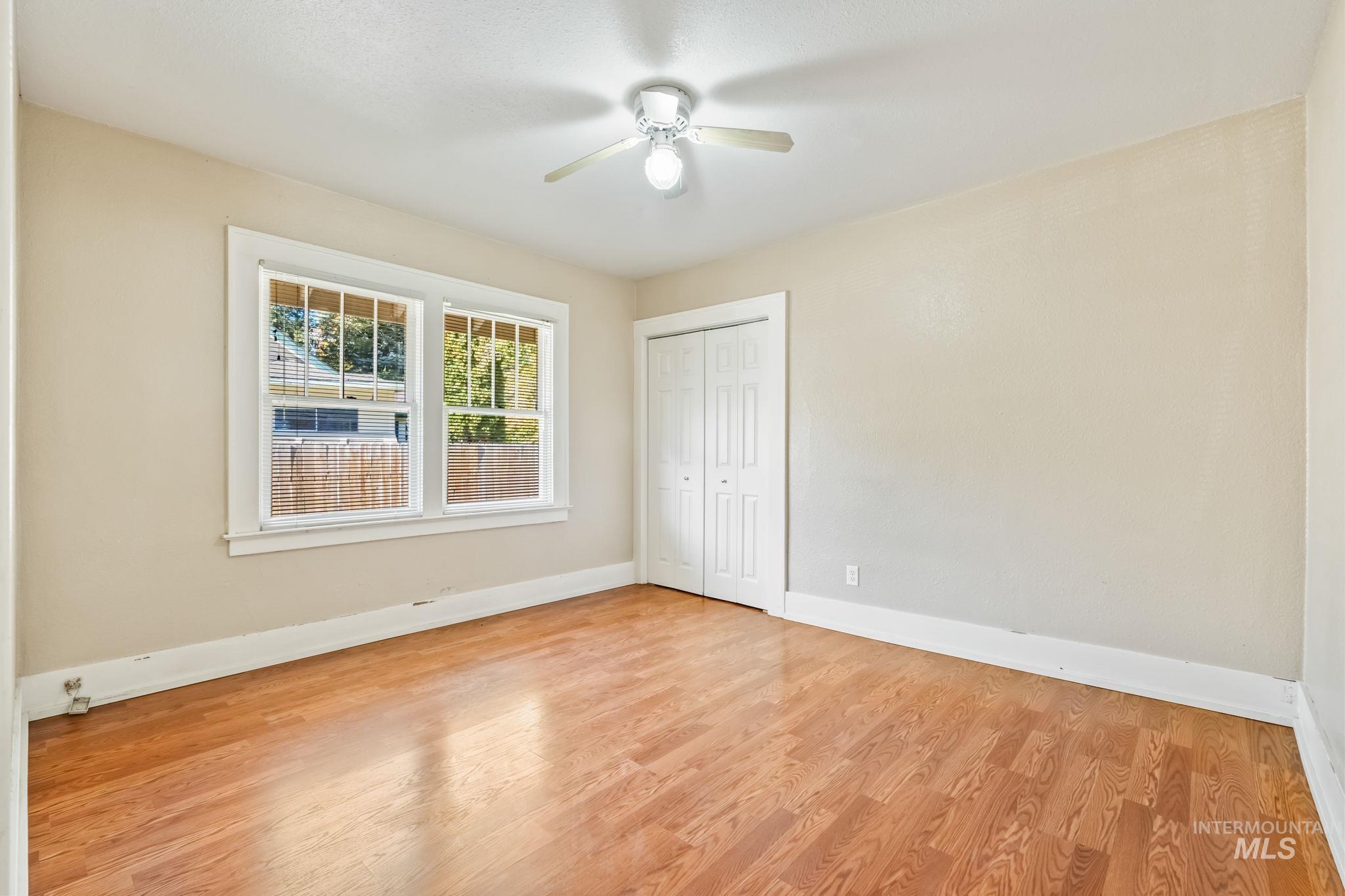 Unfurnished bedroom with light wood-type flooring, a ceiling fan, and a closet