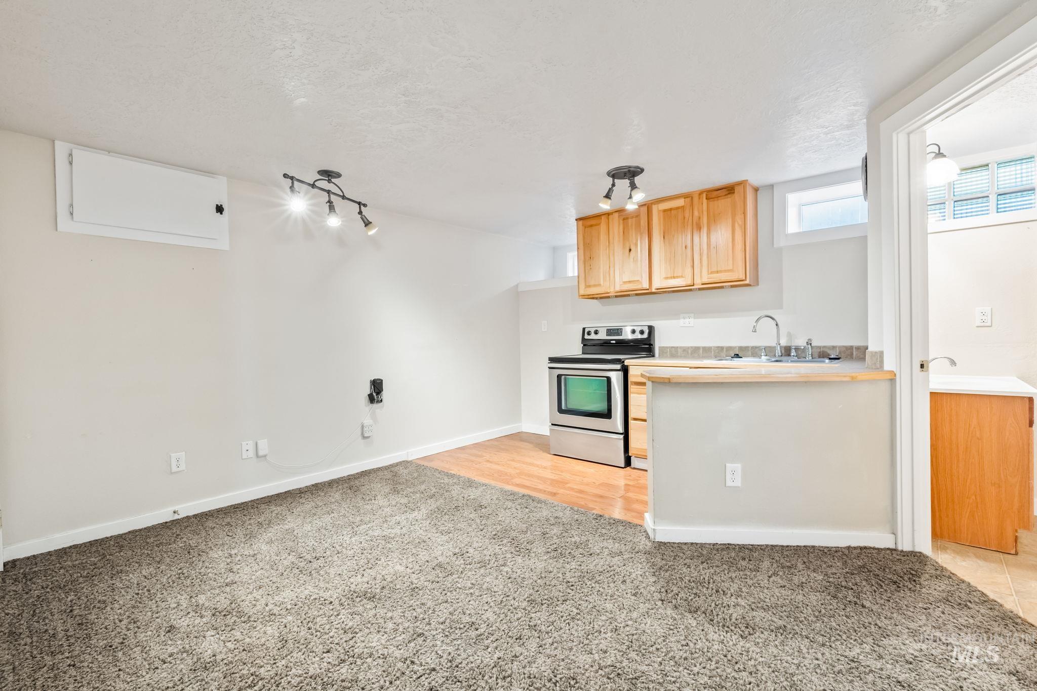 Kitchen with stainless steel range with electric cooktop, light countertops, a textured ceiling, and light carpet