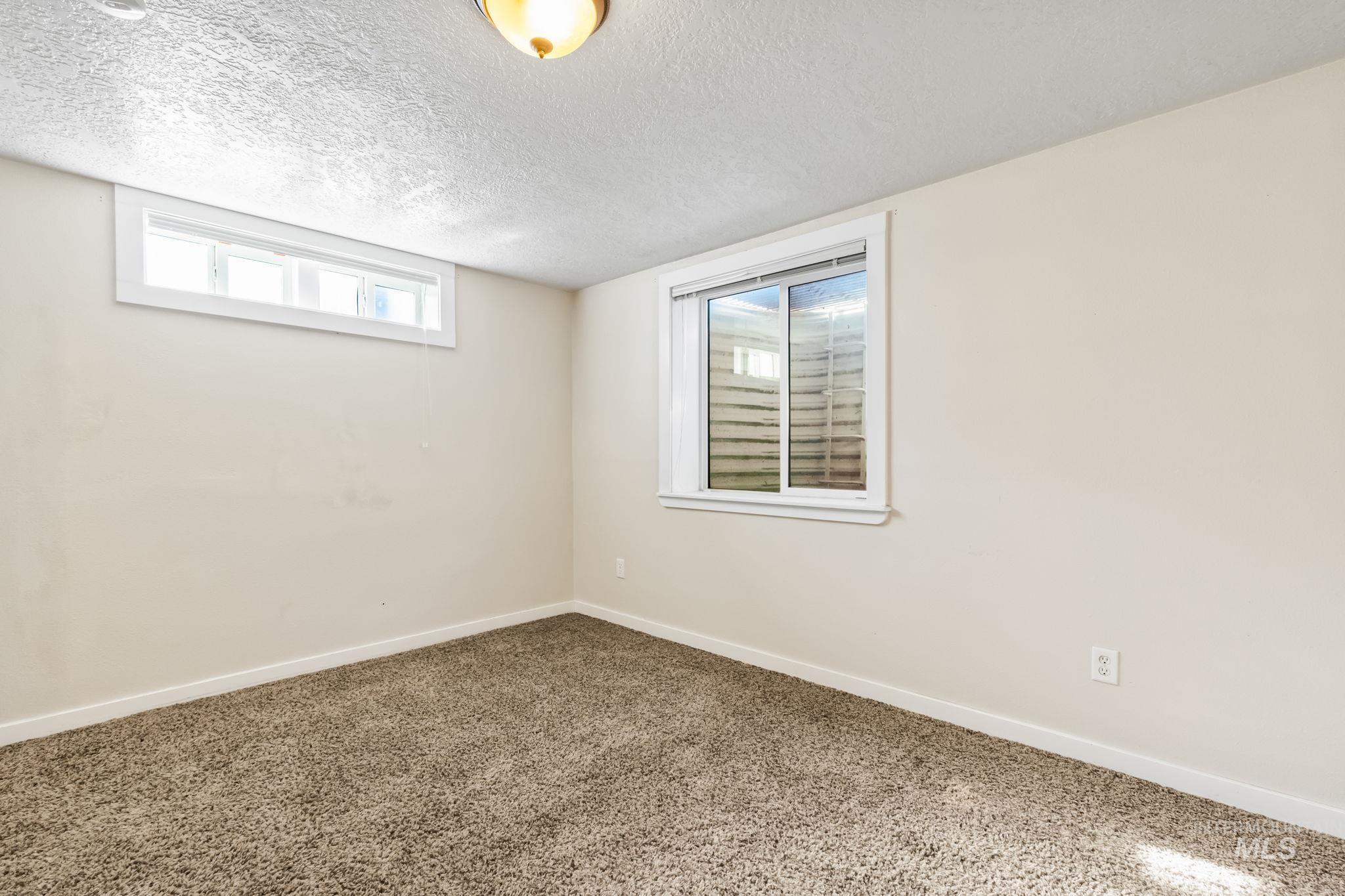 Basement with baseboards and a textured ceiling