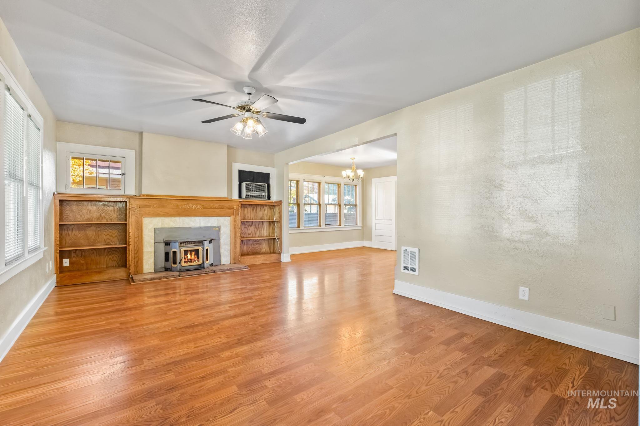 Unfurnished living room with light wood-type flooring, ceiling fan, and a chandelier