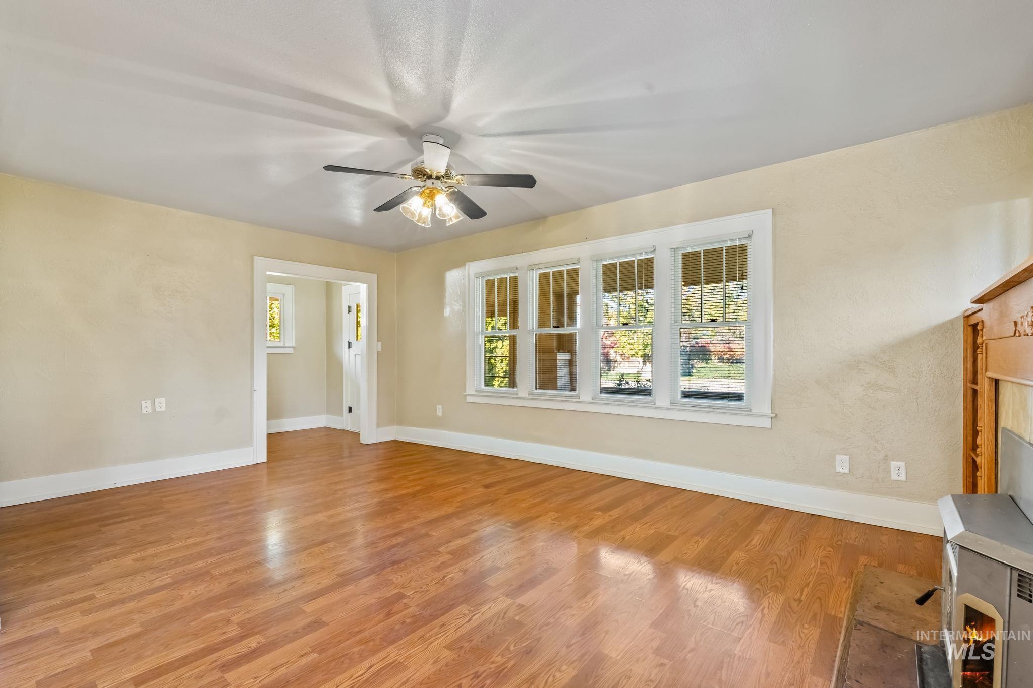 Unfurnished living room with plenty of natural light, light wood finished floors, and ceiling fan