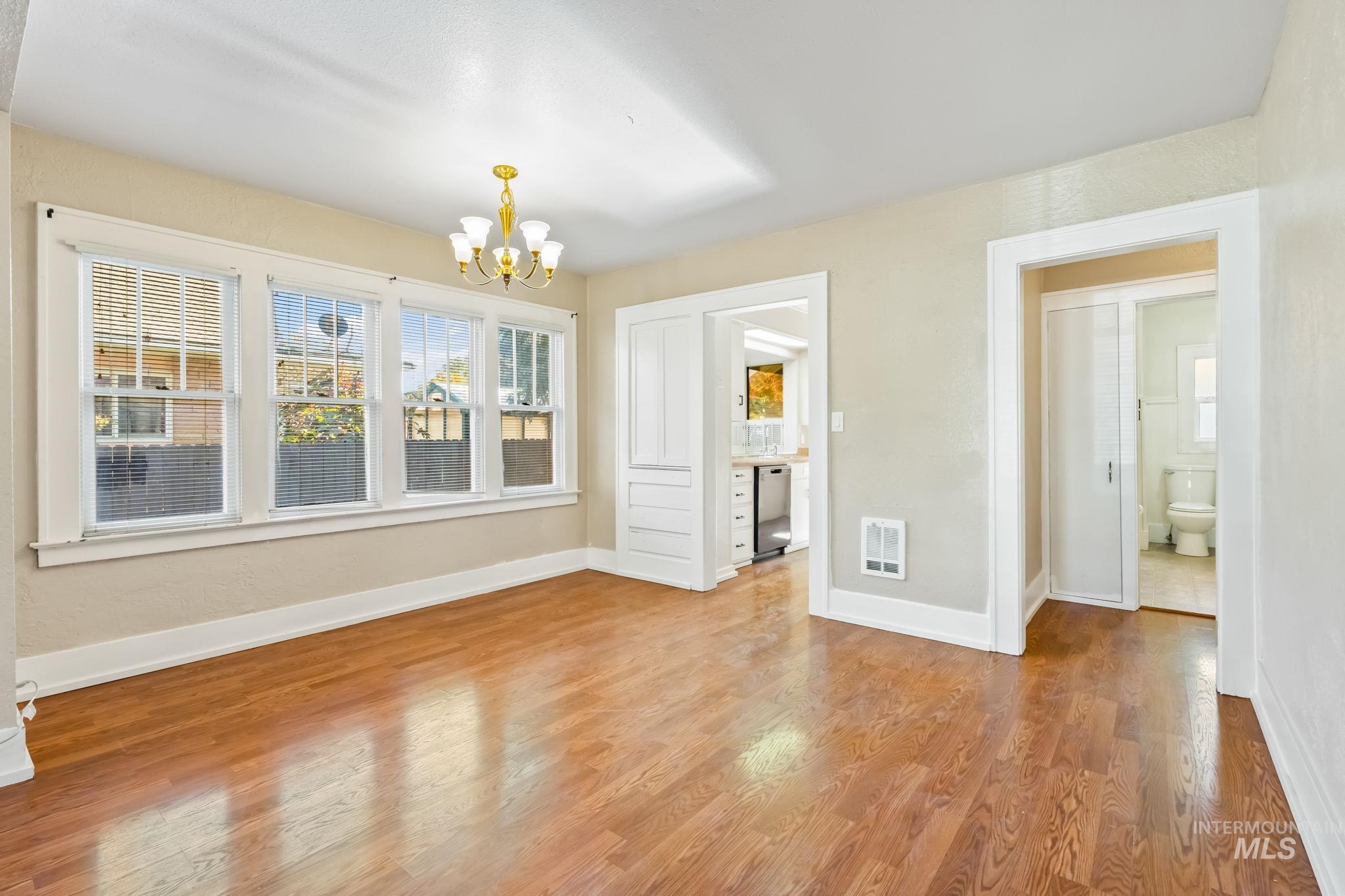 Unfurnished dining area featuring wood finished floors and a chandelier