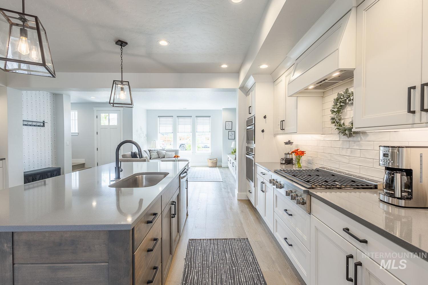 Kitchen with recessed lighting, light stone countertops, open floor plan, appliances with stainless steel finishes, and light wood-style flooring