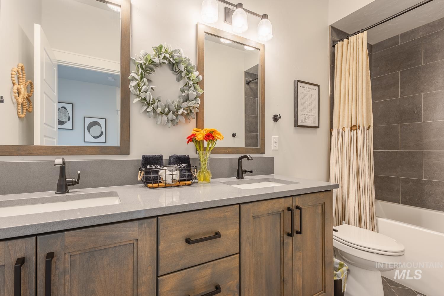 Full bath with double vanity, shower / bath combo with shower curtain, and tile patterned floors