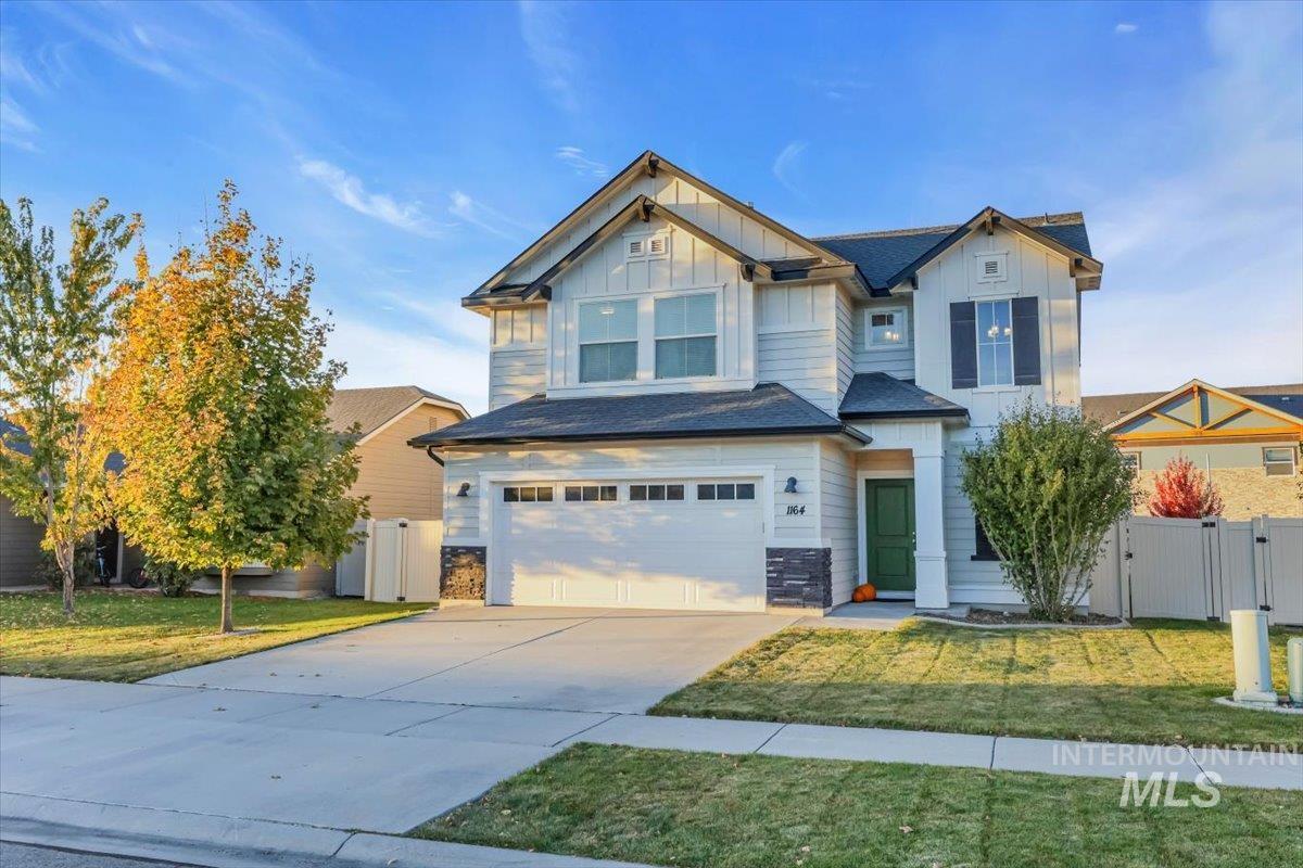 Craftsman house featuring board and batten siding, driveway, an attached garage, and a gate