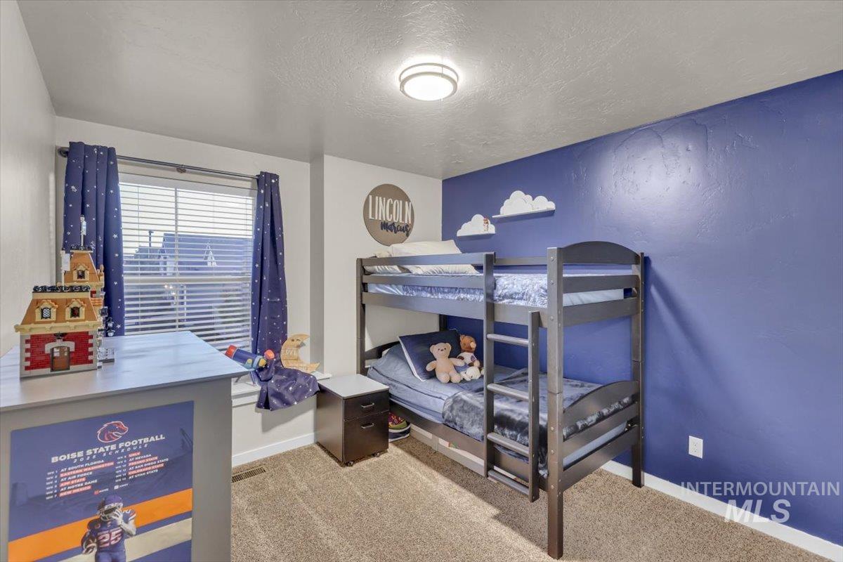 Bedroom featuring light colored carpet and a textured ceiling