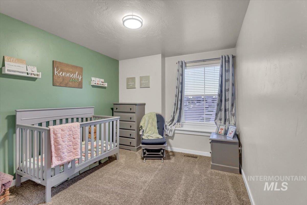 Bedroom featuring carpet, a crib, and a textured ceiling