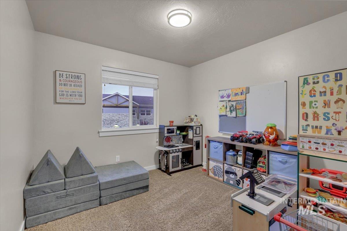 Playroom with light colored carpet and a textured ceiling