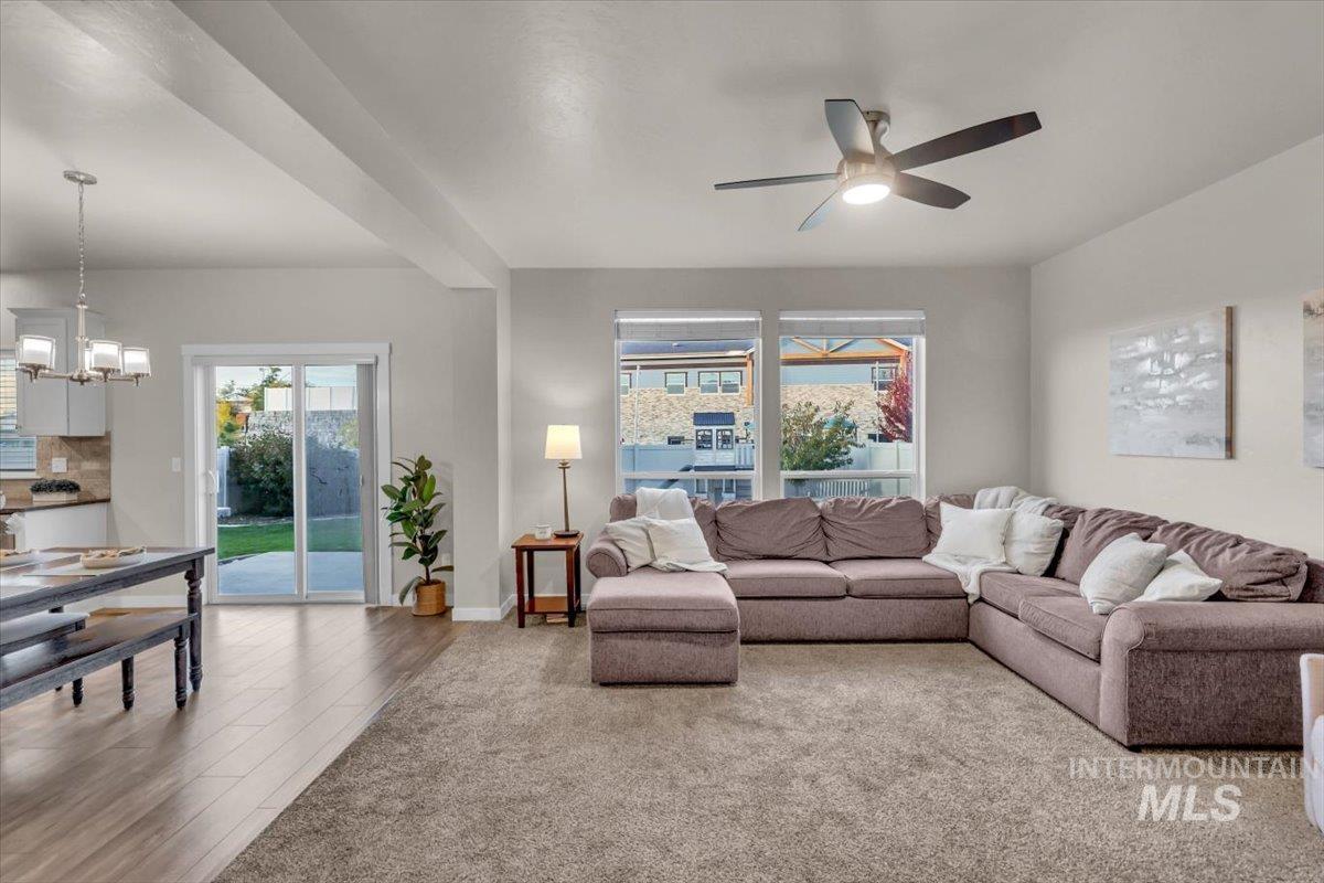 Living area featuring light wood-style floors, a chandelier, and ceiling fan