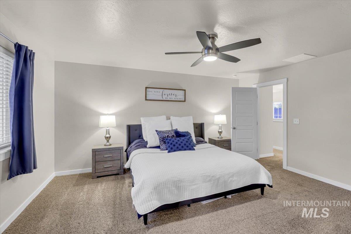 Bedroom with carpet floors, a textured ceiling, and a ceiling fan