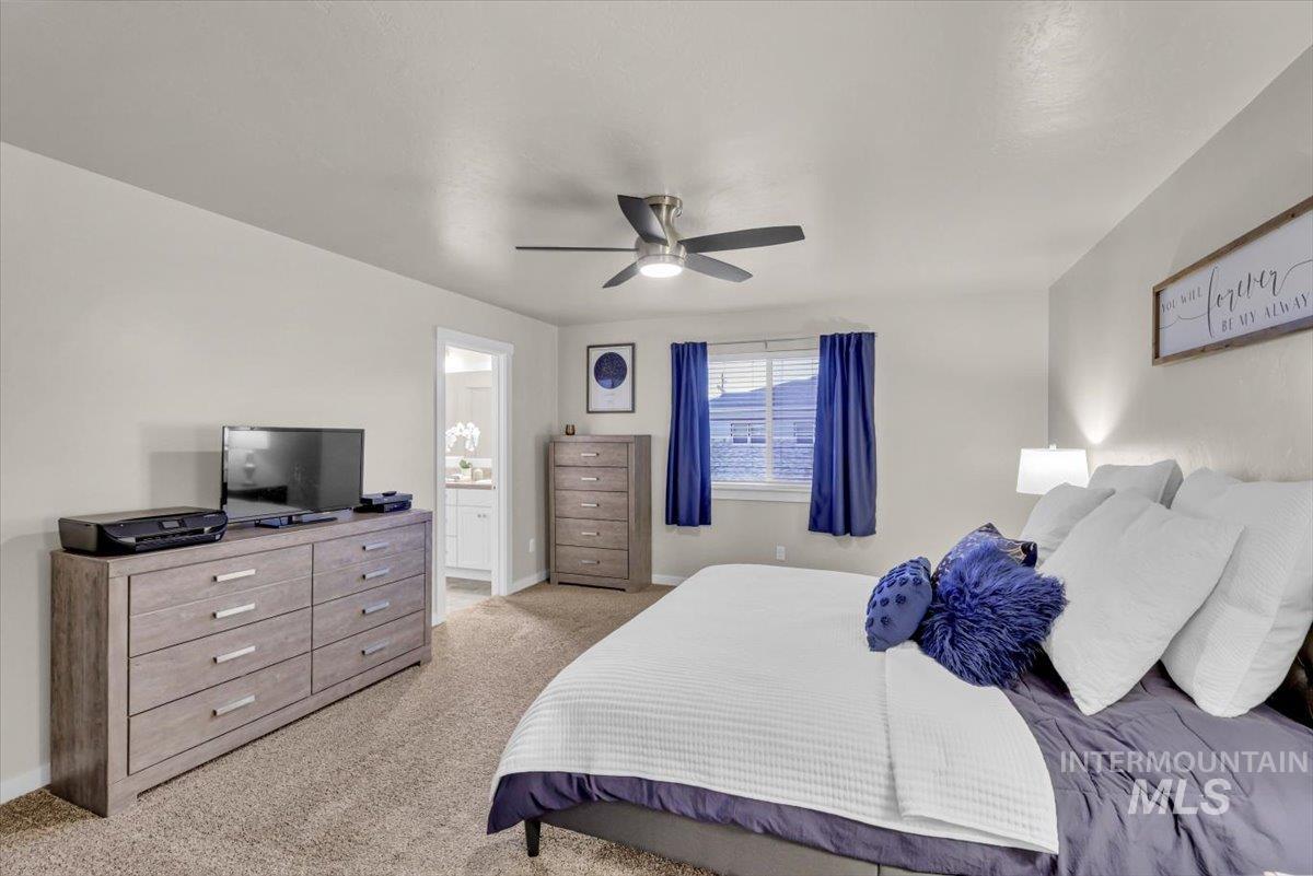 Bedroom featuring light carpet, a ceiling fan, and ensuite bath
