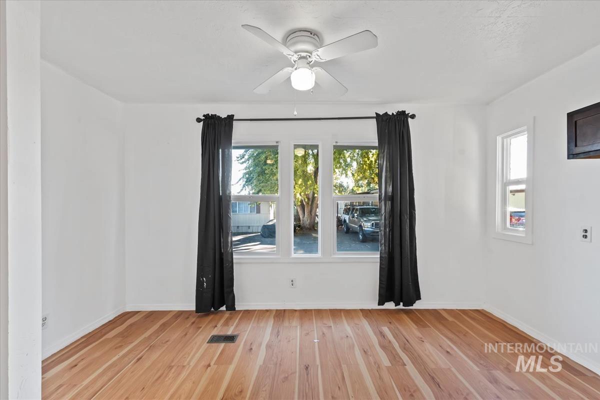 Unfurnished room with healthy amount of natural light, light wood finished floors, and a ceiling fan