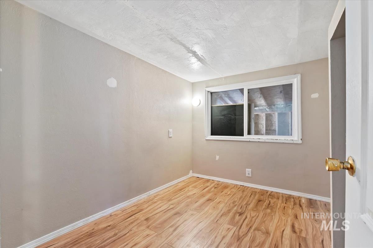 Unfurnished room featuring light wood finished floors and a textured ceiling