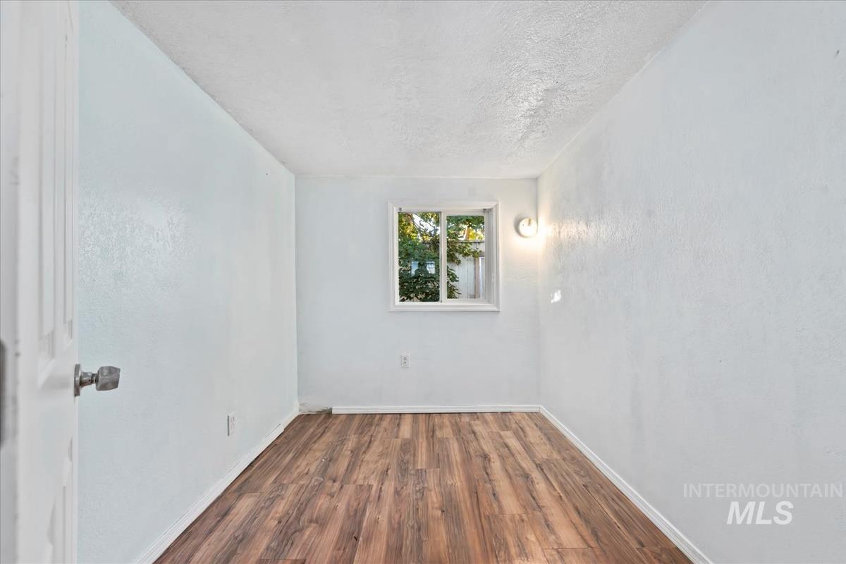Unfurnished room with dark wood-style flooring and a textured ceiling