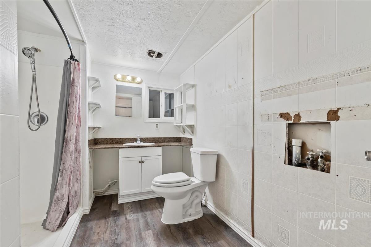 Bathroom featuring vanity, dark wood-style flooring, curtained shower, and a textured ceiling