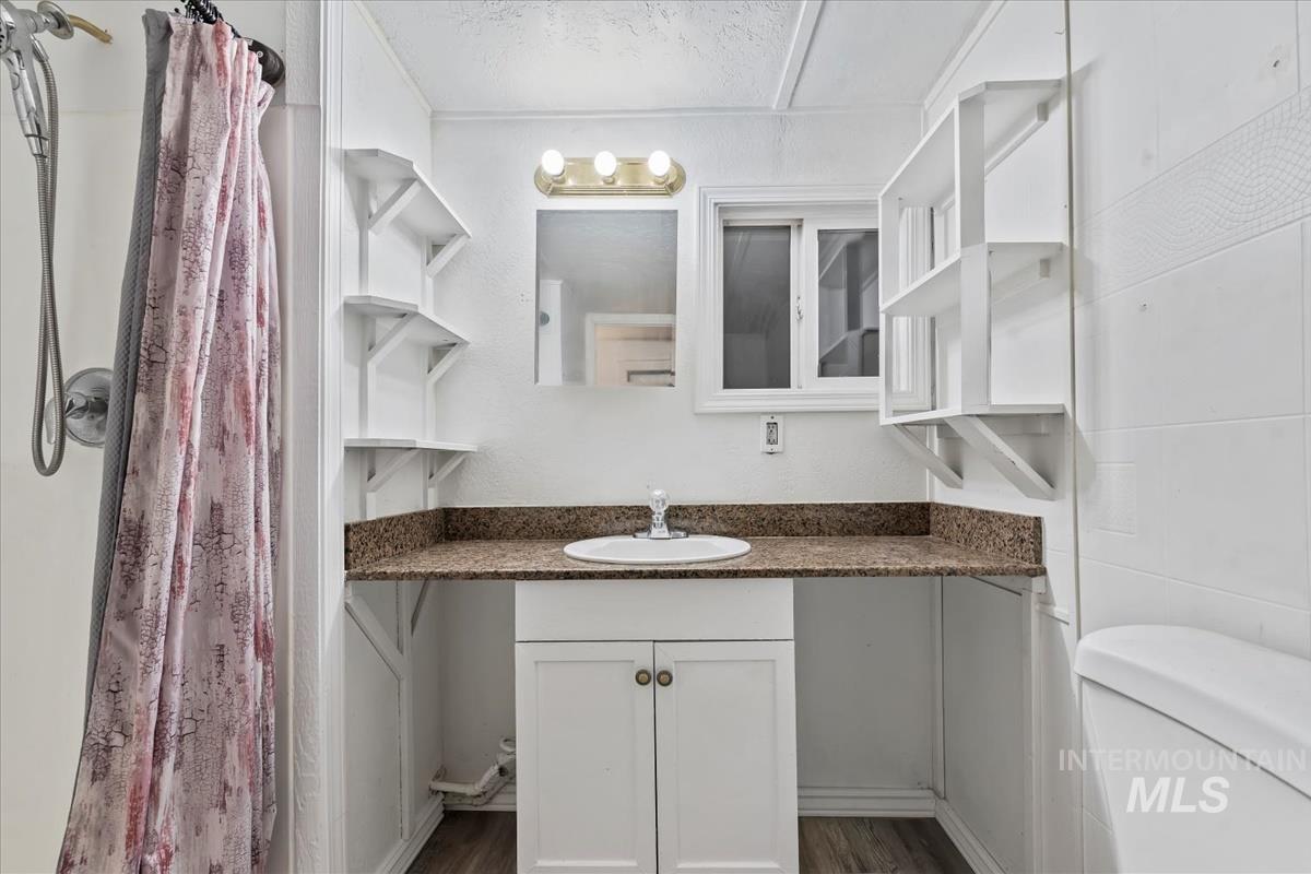 Bathroom featuring vanity, a shower with shower curtain, and dark wood-style flooring