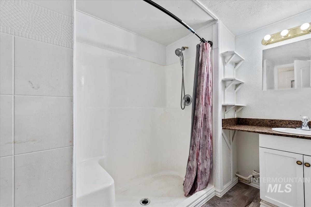 Bathroom with vanity, a stall shower, and a textured ceiling