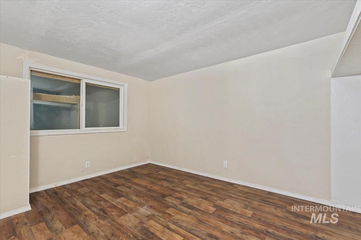 Spare room with a textured ceiling and dark wood-style floors
