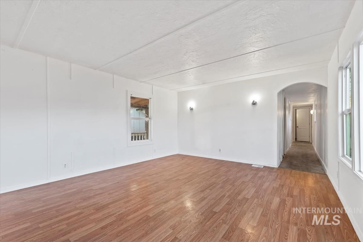 Spare room with light wood-type flooring, arched walkways, and a textured ceiling