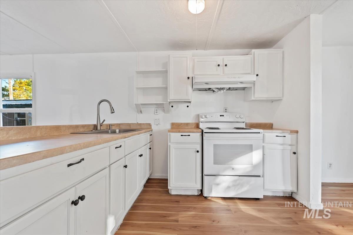 Kitchen featuring white cabinetry, white electric stove, open shelves, light countertops, and light wood-style floors