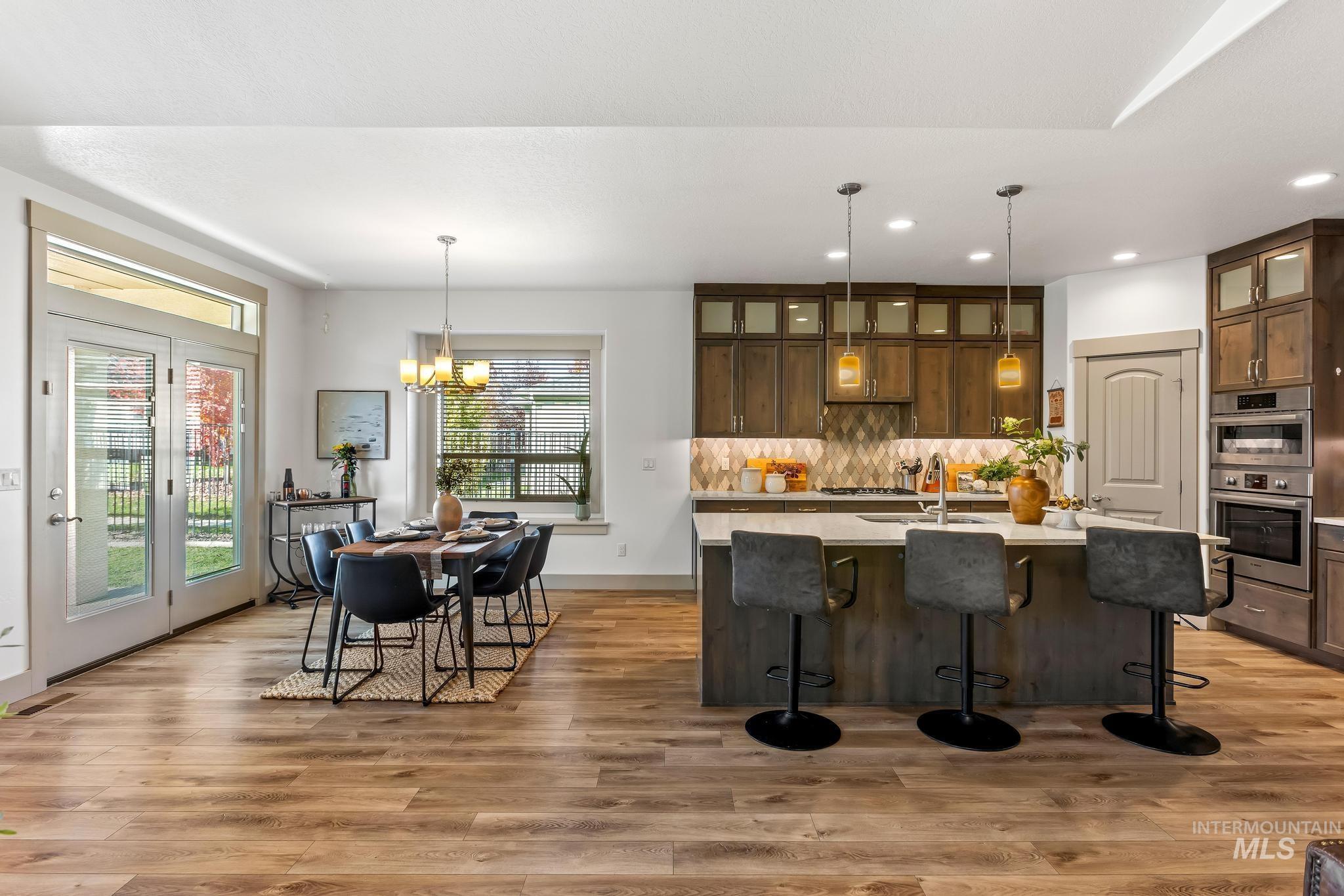 Kitchen featuring pendant lighting, a breakfast bar, glass insert cabinets, a chandelier, and recessed lighting