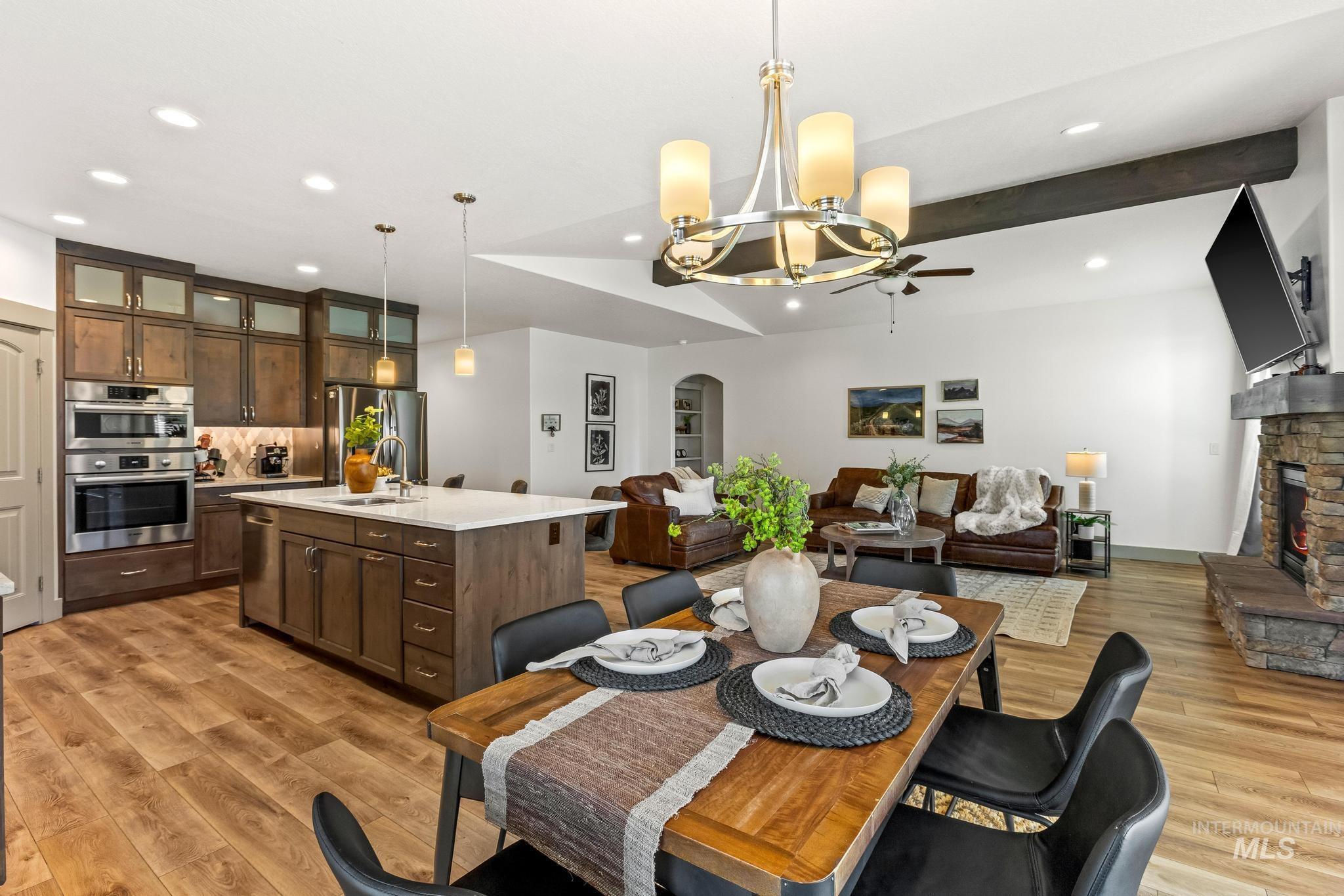 Dining area featuring arched walkways, light wood finished floors, a stone fireplace, recessed lighting, and a ceiling fan