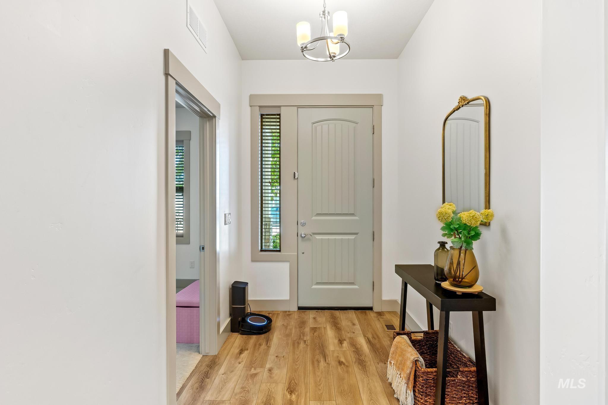 Entryway with light wood-style flooring and a chandelier