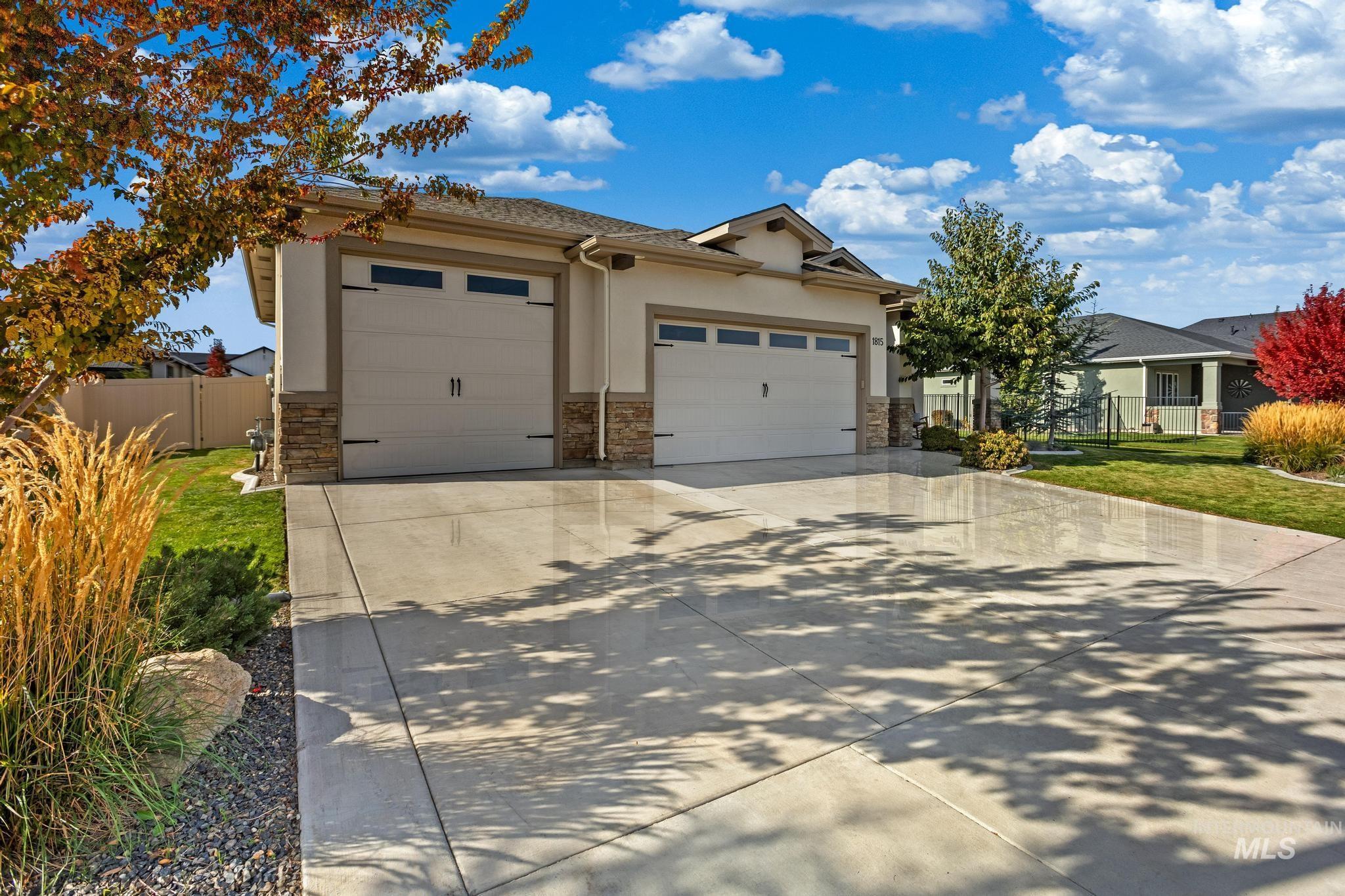 View of front of property with driveway, stone siding, a garage, and stucco siding