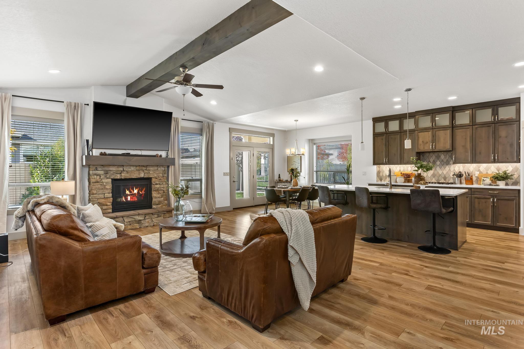 Living room featuring light wood-style floors, recessed lighting, a stone fireplace, ceiling fan, and a chandelier
