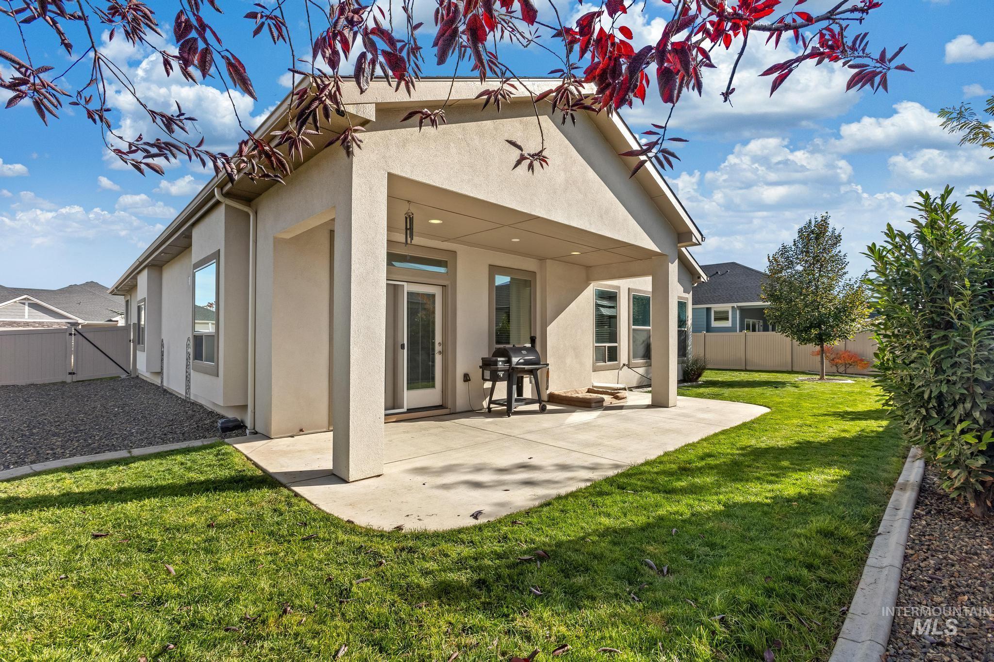 Rear view of property with stucco siding, a fenced backyard, and a patio area