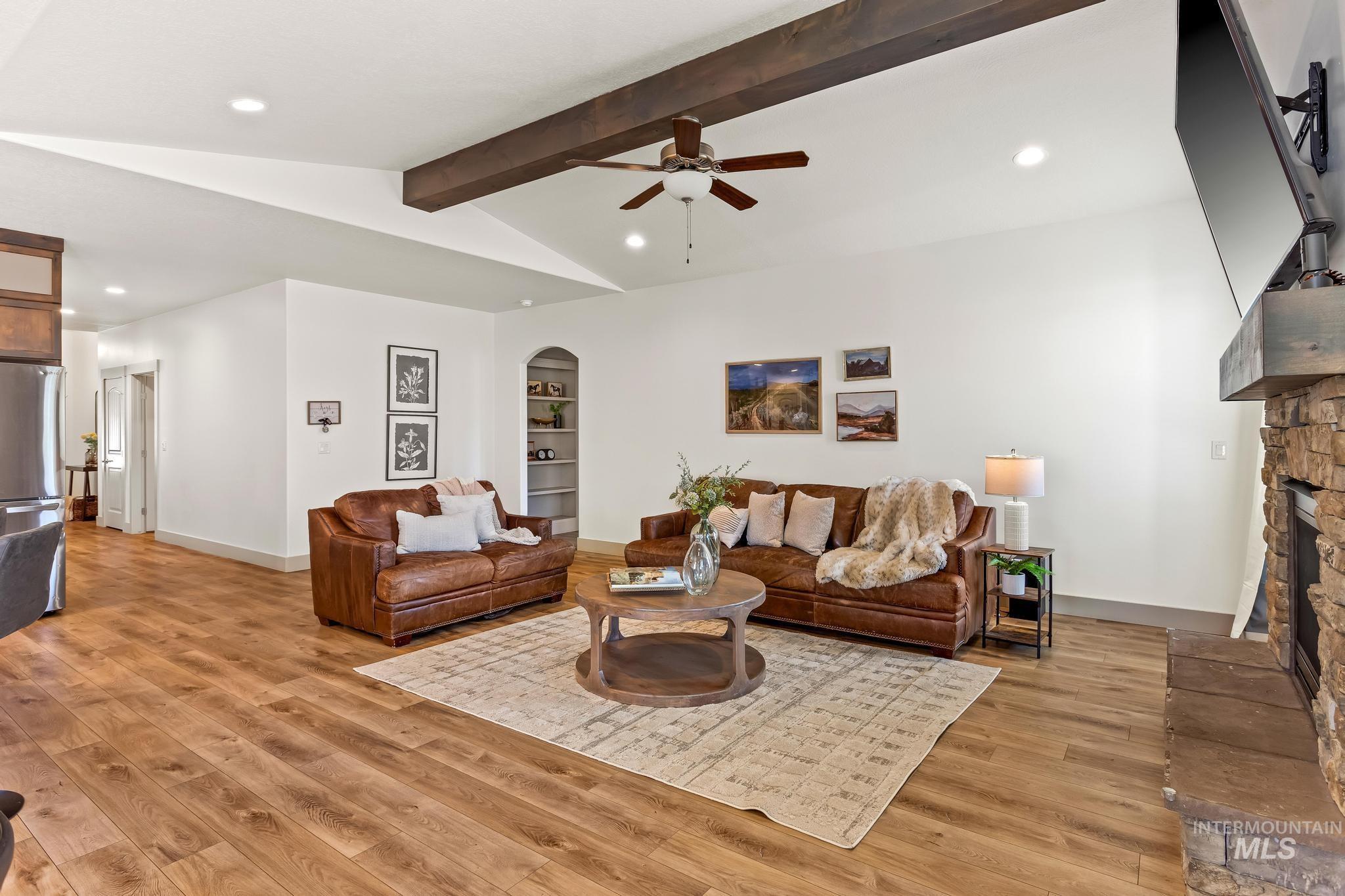Living room featuring recessed lighting, a ceiling fan, light wood-style floors, a stone fireplace, and arched walkways