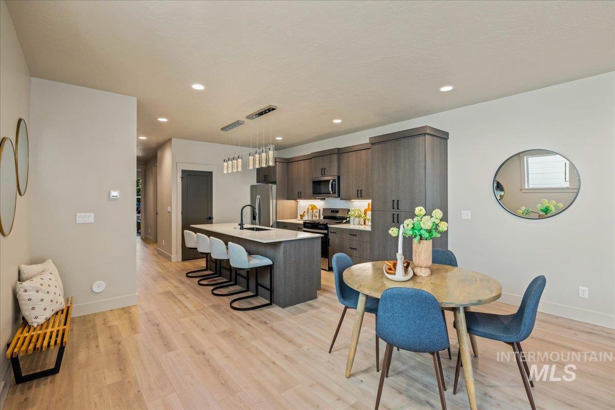Dining area with light wood finished floors and recessed lighting