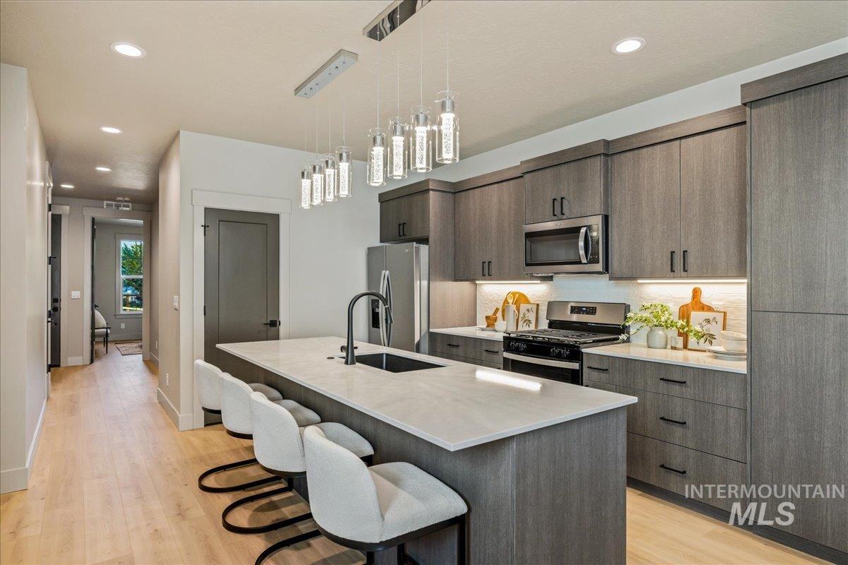 Kitchen featuring recessed lighting, stainless steel appliances, a breakfast bar area, a kitchen island with sink, and pendant lighting