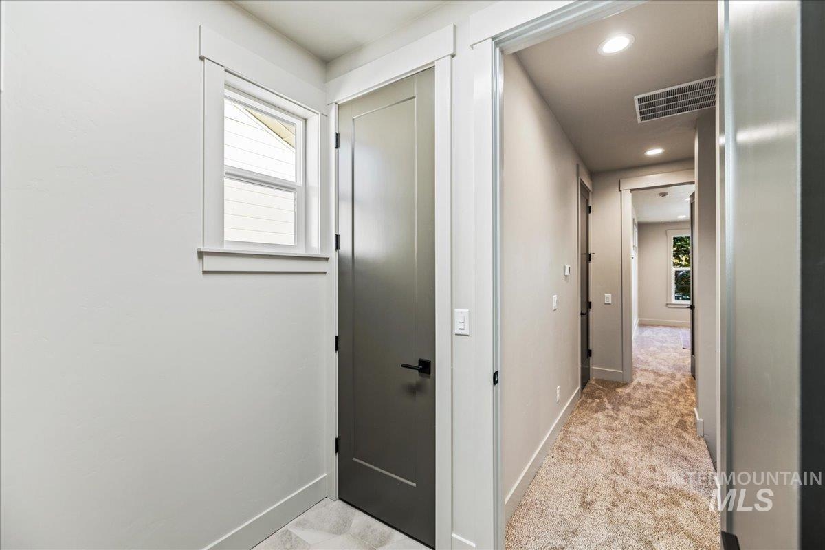 Hallway featuring plenty of natural light, recessed lighting, and light colored carpet