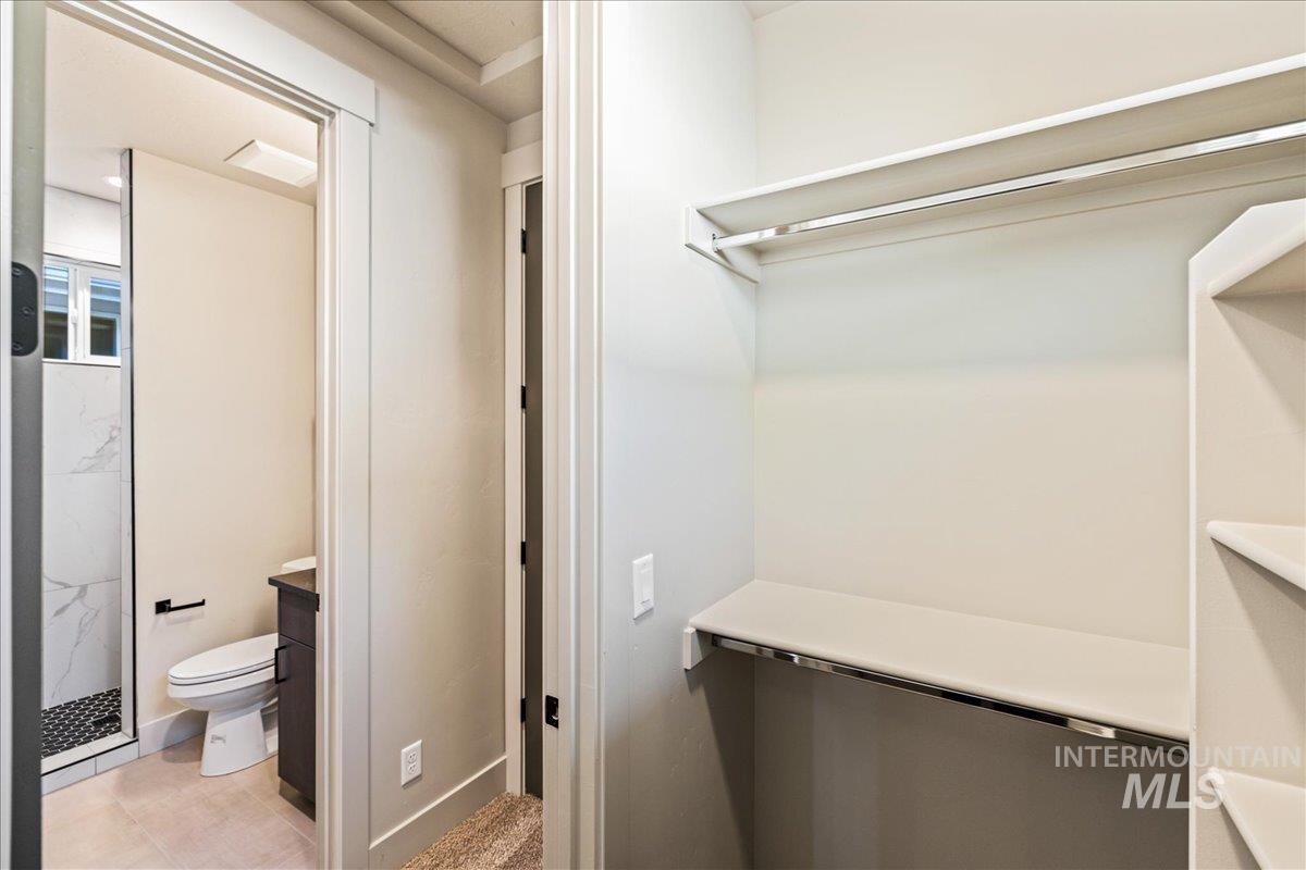 Full bathroom featuring vanity, a marble finish shower, and light tile patterned flooring