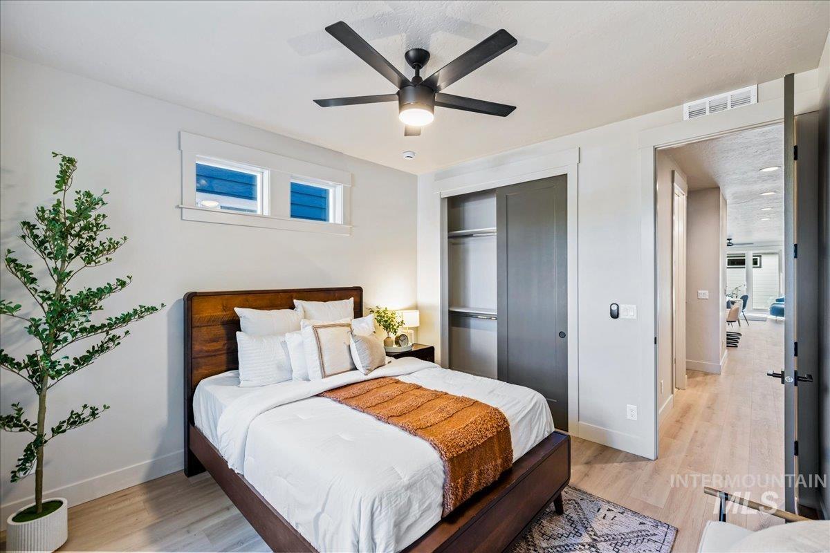 Bedroom with light wood finished floors, a closet, and a ceiling fan
