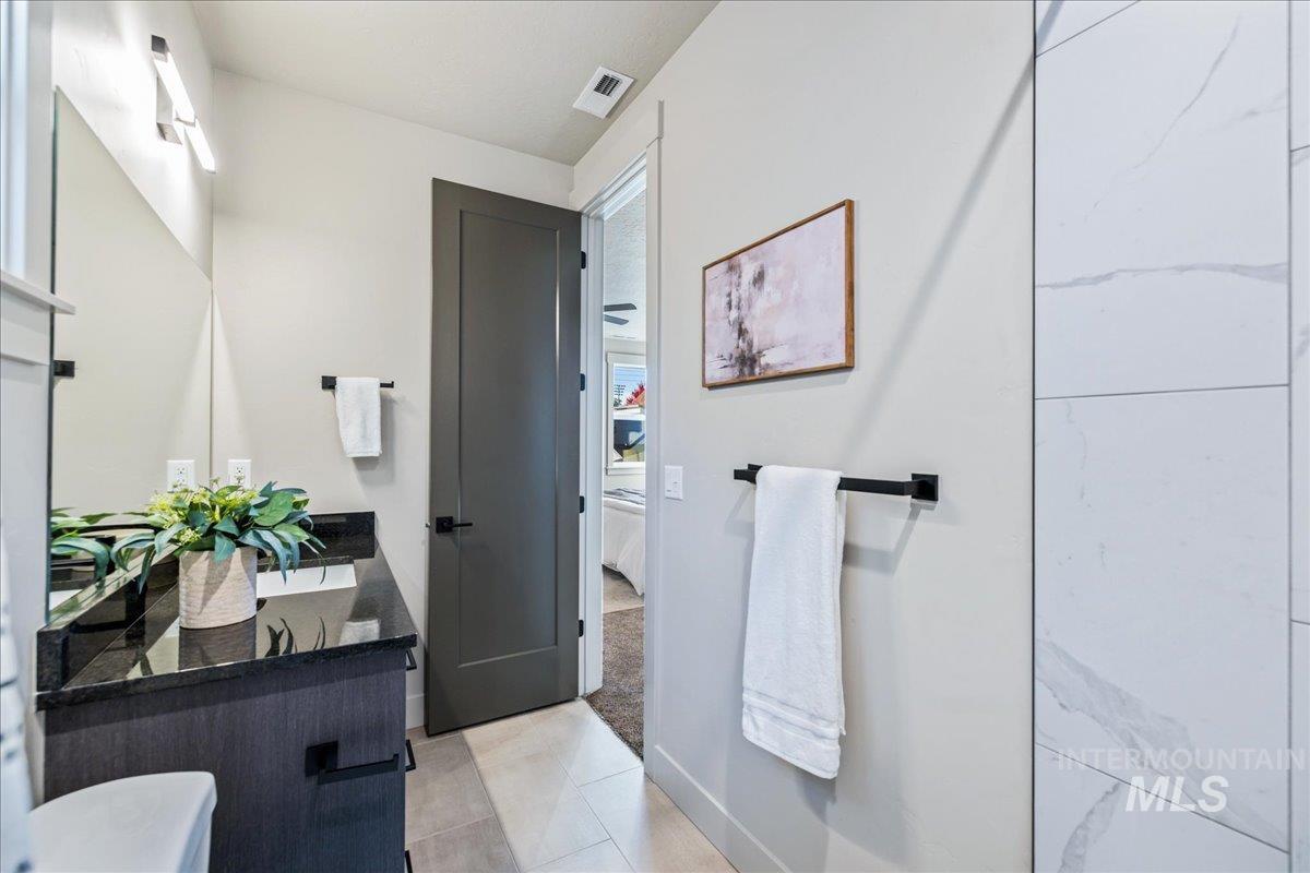 Full bath featuring double vanity, ensuite bathroom, light tile patterned floors, and light carpet
