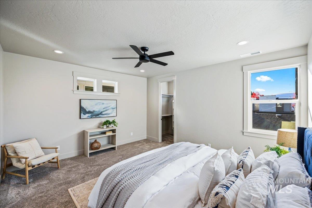 Carpeted bedroom with a walk in closet, a textured ceiling, ceiling fan, and recessed lighting
