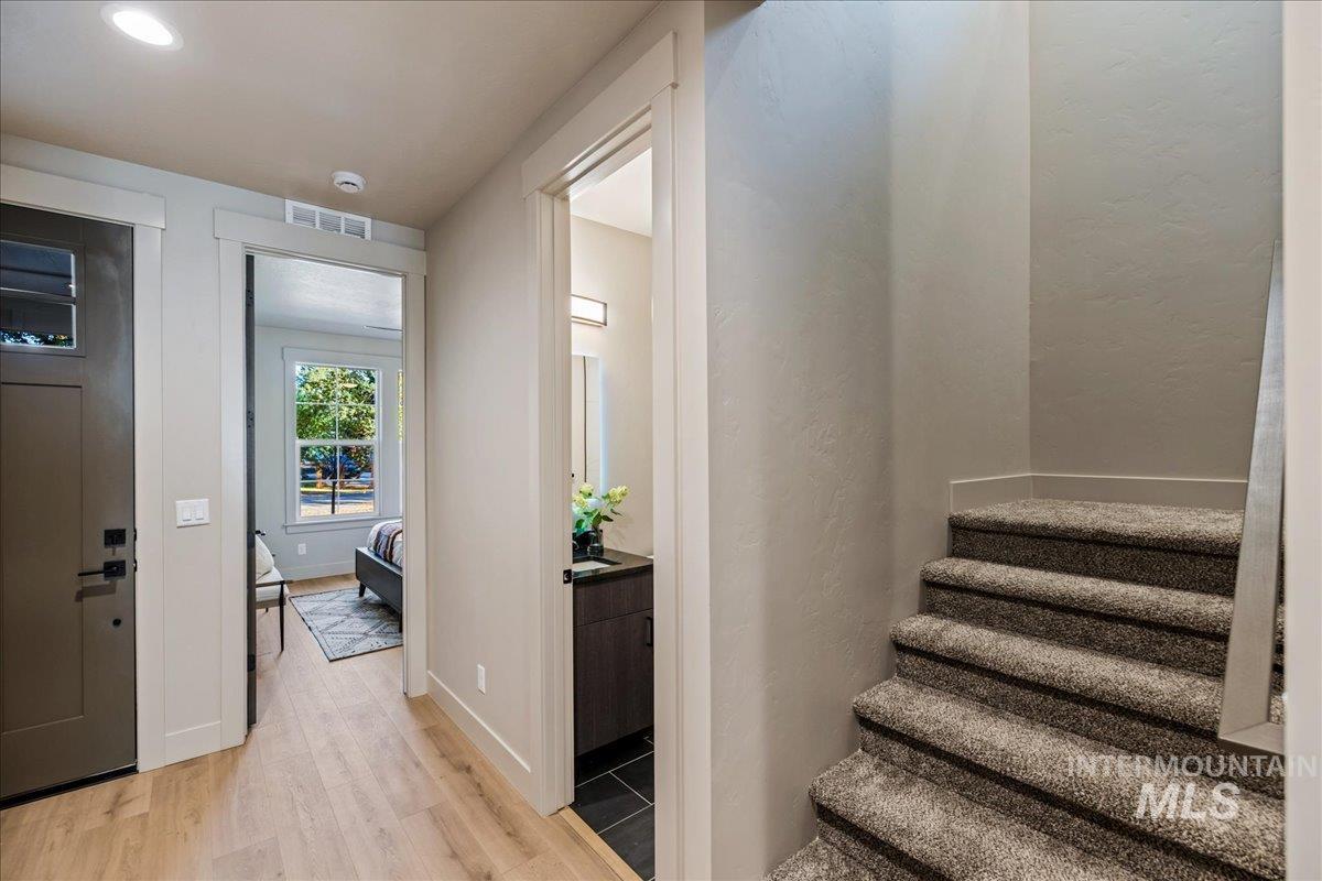 Entryway with light wood-type flooring, stairs, and a textured wall