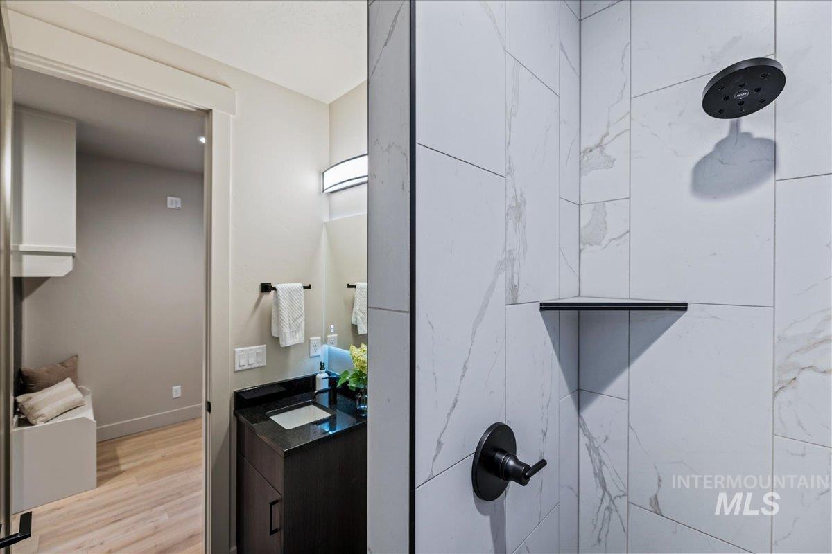 Bathroom with vanity, tiled shower, and light wood finished floors