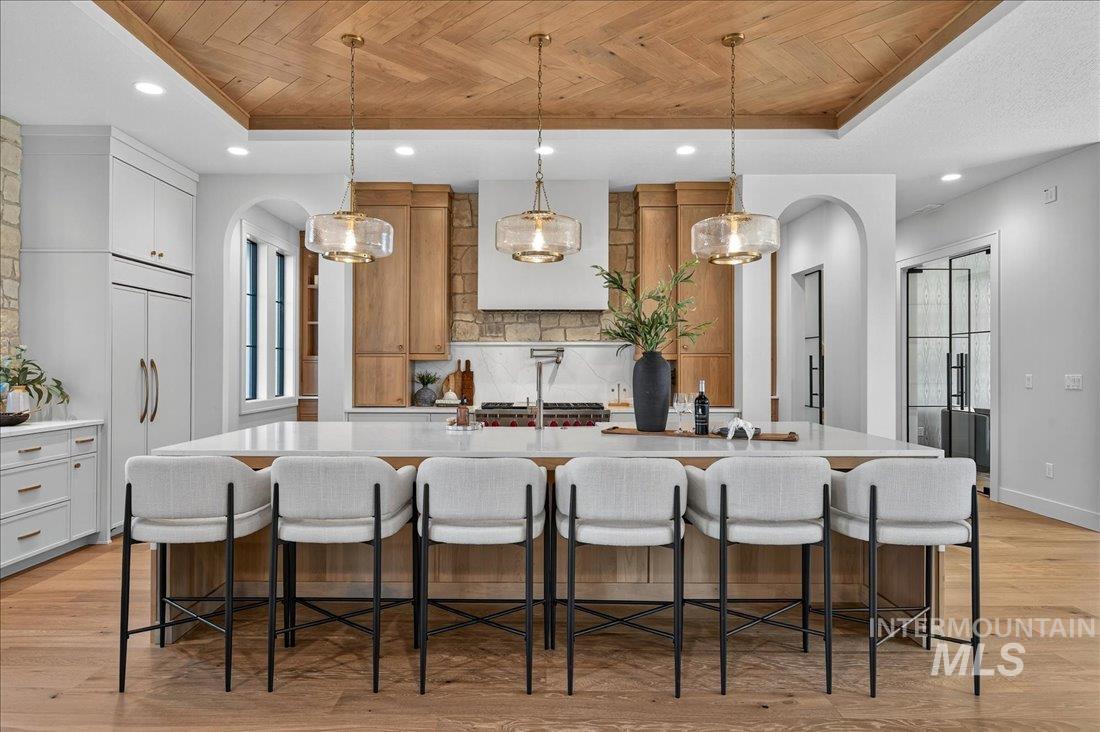 Kitchen featuring arched walkways, pendant lighting, light wood-style flooring, a kitchen bar, and recessed lighting