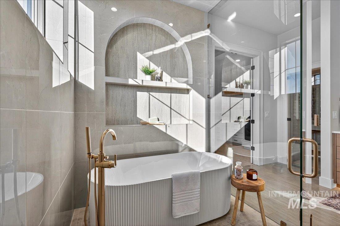 Bathroom with a freestanding tub, tile walls, and wood finished floors