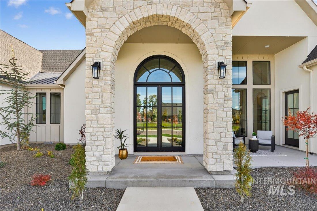 View of exterior entry with stone siding, french doors, stucco siding, and a metal roof