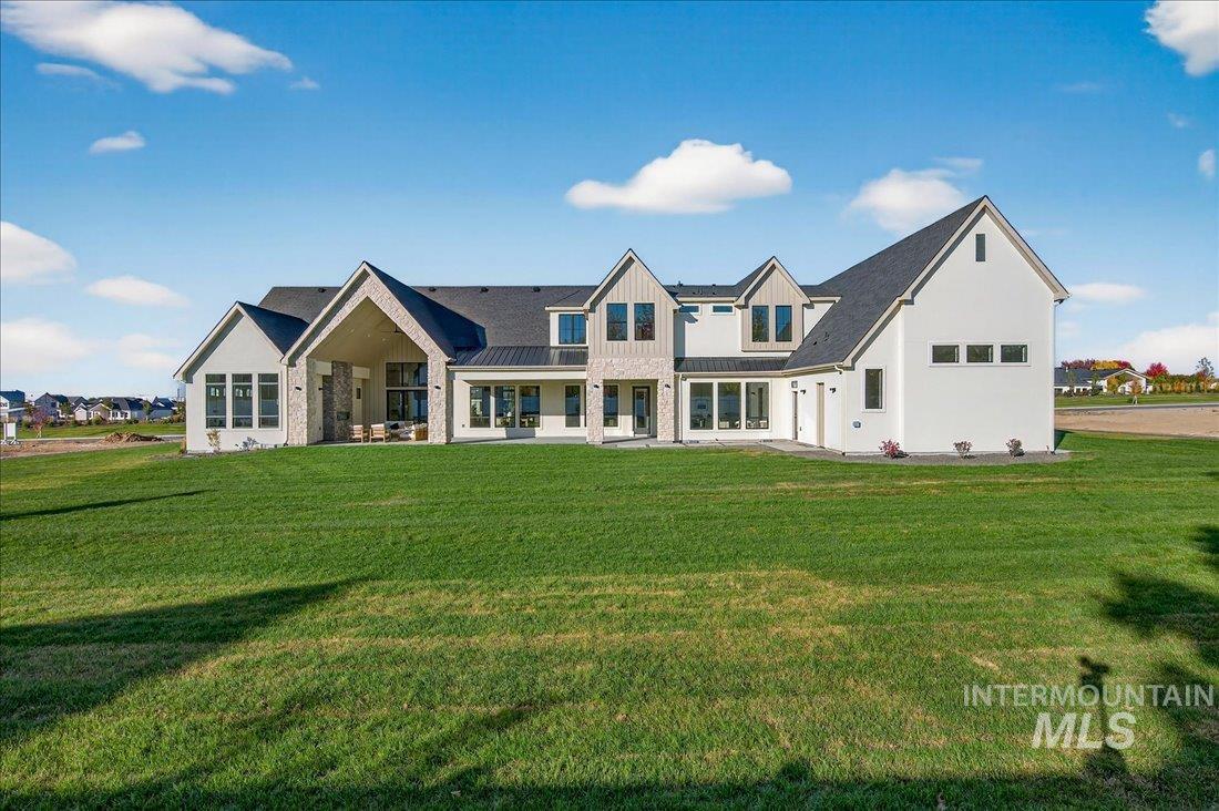 Back of property with a yard, a patio, a standing seam roof, and a metal roof