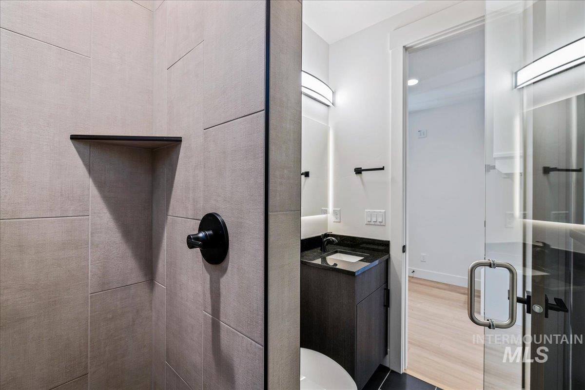 Full bath with vanity, a shower stall, and dark wood-type flooring