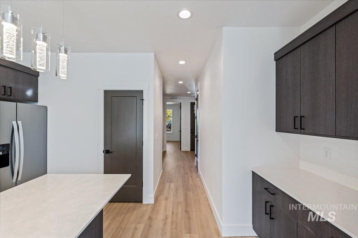 Kitchen featuring dark brown cabinets, modern cabinets, recessed lighting, light wood finished floors, and stainless steel refrigerator with ice dispenser