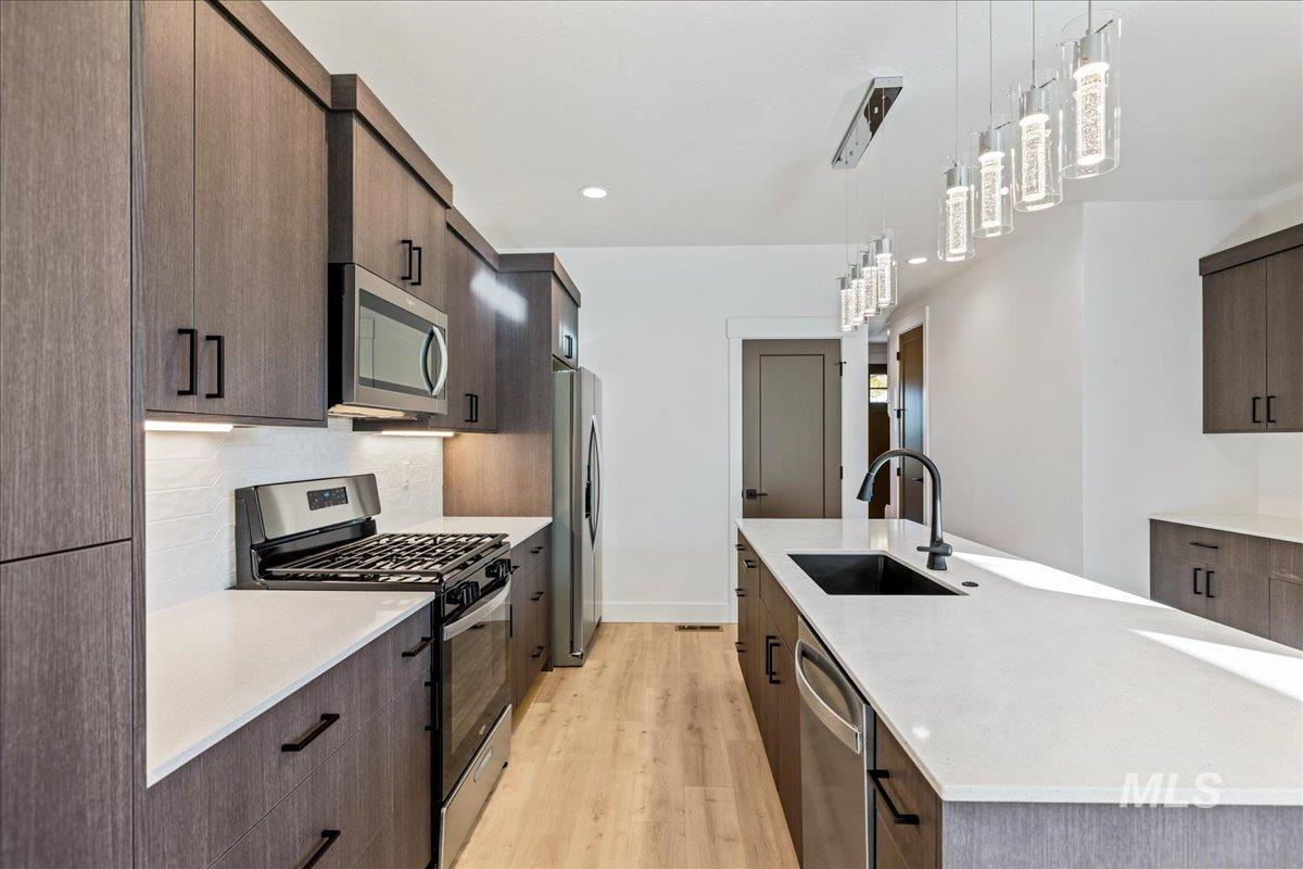 Kitchen with appliances with stainless steel finishes, modern cabinets, dark brown cabinets, and recessed lighting
